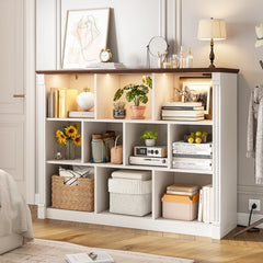 Storage in white cabinets includes books, potted plants, and other miscellaneous items